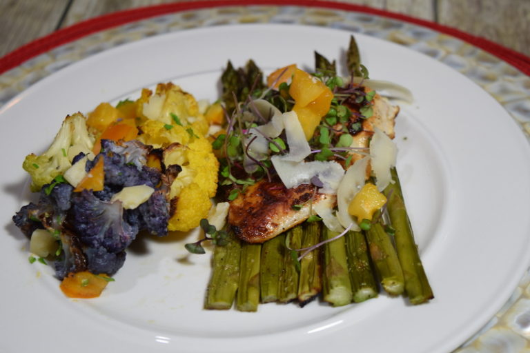 Chicken covered in micro greens on a bed of Asparagus