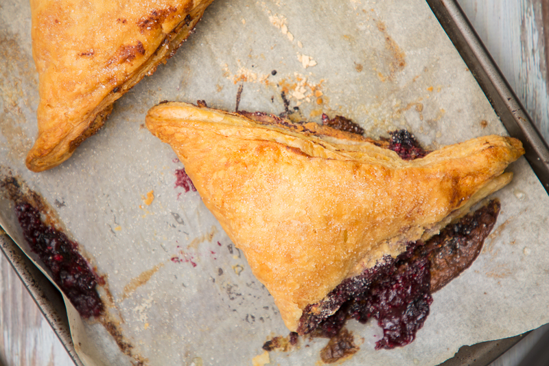 blue raspberry cheesecake turnovers on a baking sheet