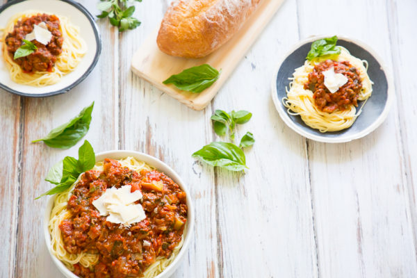 Plates of spaghetti sauce and pasta with rustic loaf of bread
