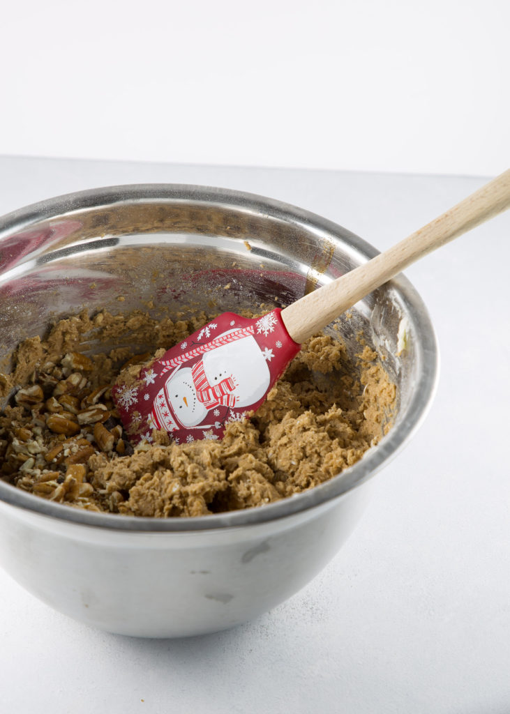 spiced oatmeal chocolate chip cookie recipe in a bowl with a Christmas spatula