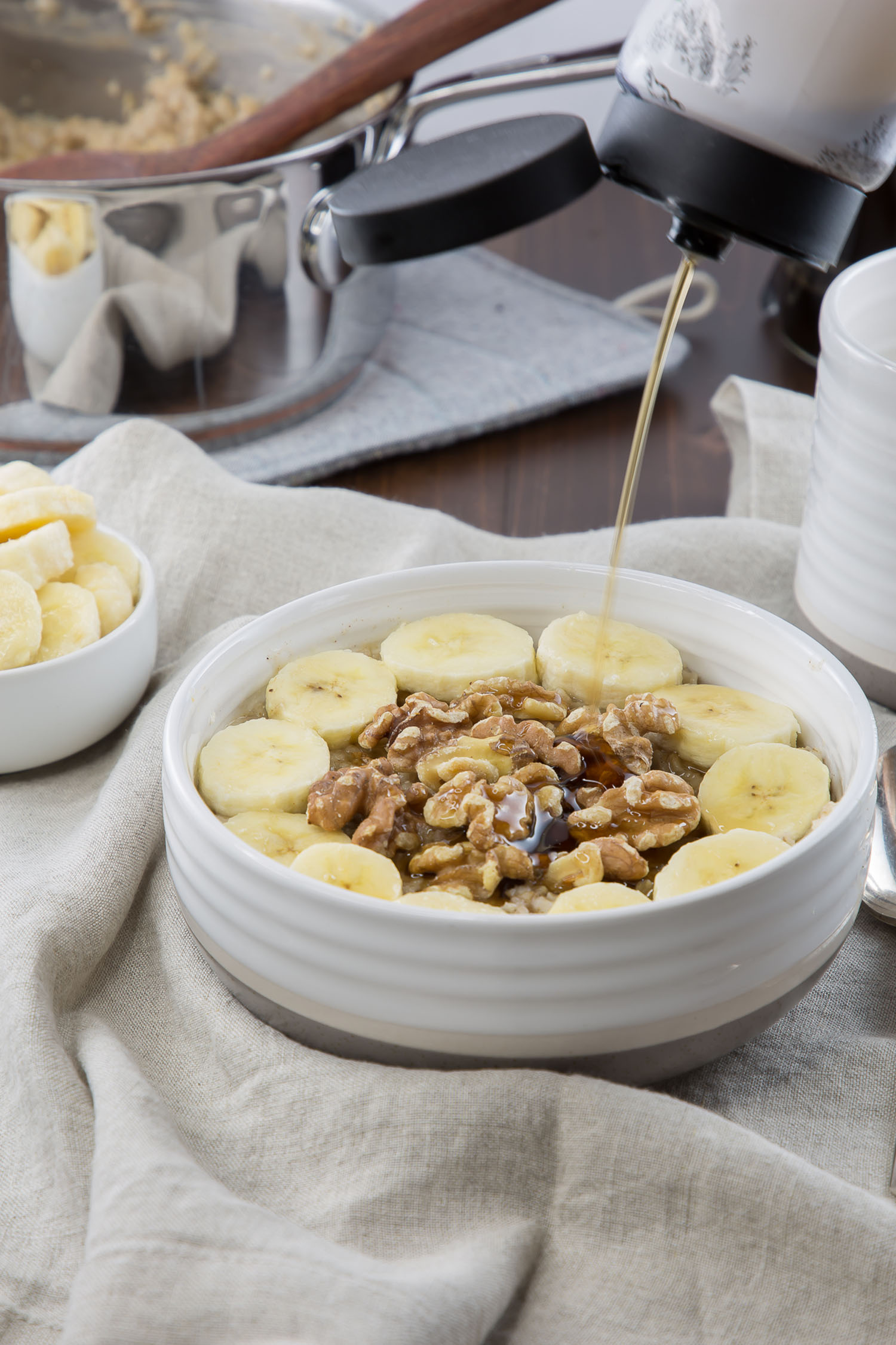 banana nut oatmeal with maple syrup pouring on it