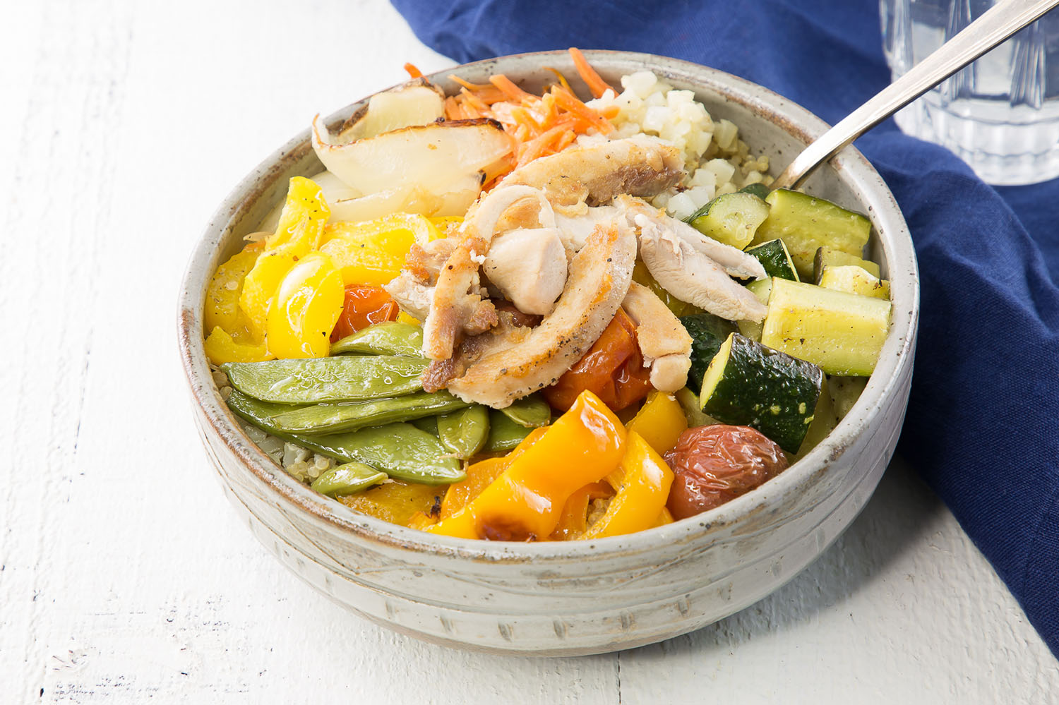 close up of roasted chicken and veggies in a rice bowl