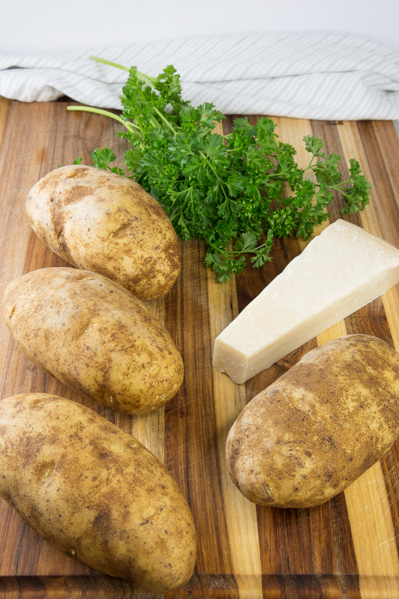 russet potatoes, parsley, and parm on a cutting board